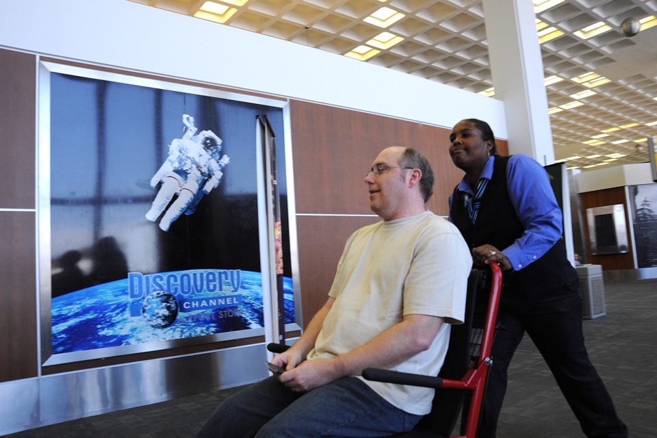 Airport employee assisting a traveller with reduced mobility