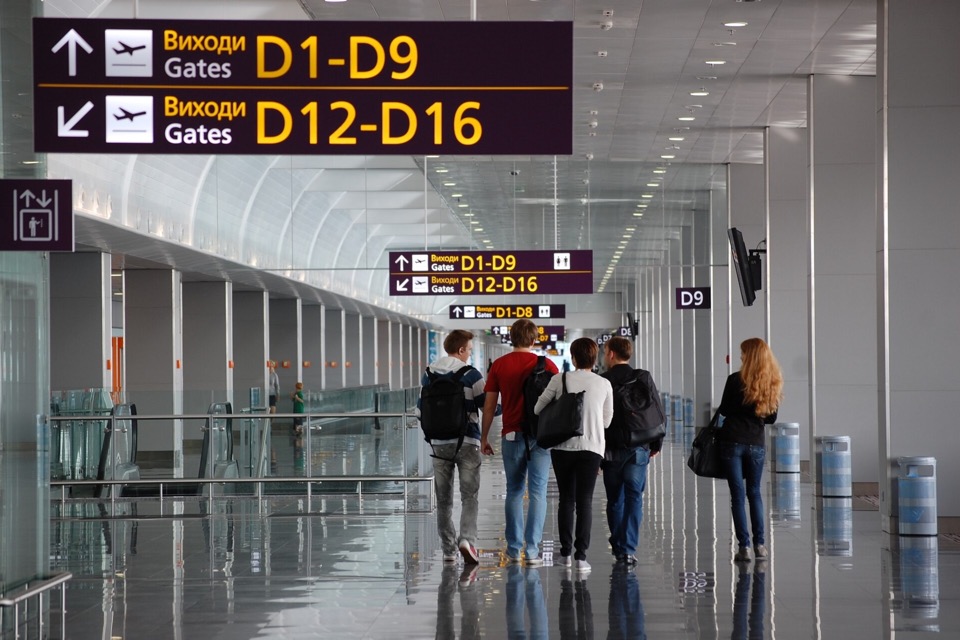 Travellers walking with carry-on bags through an airport terminal